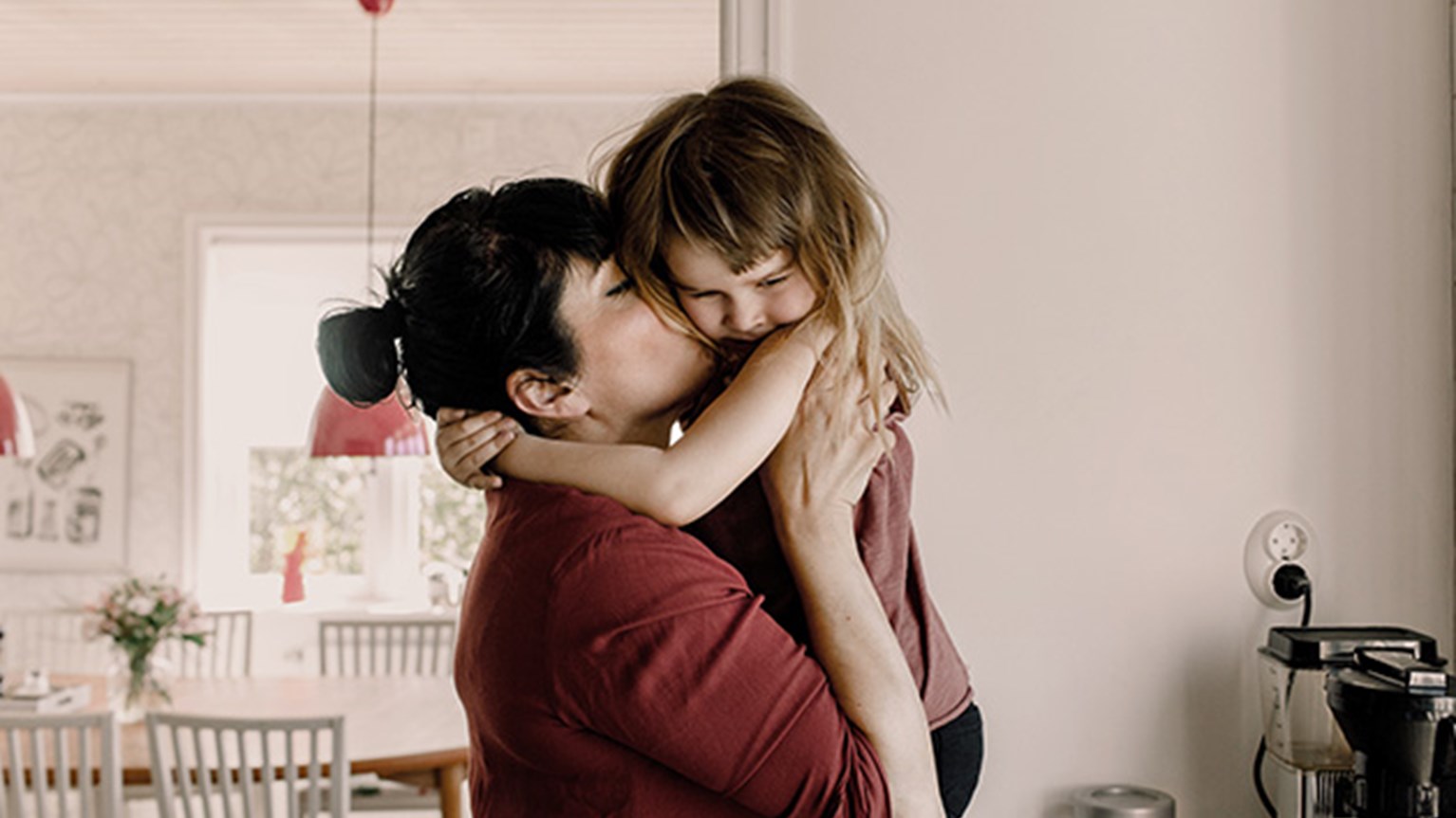 Mamma pussar sin dotter på kinden
